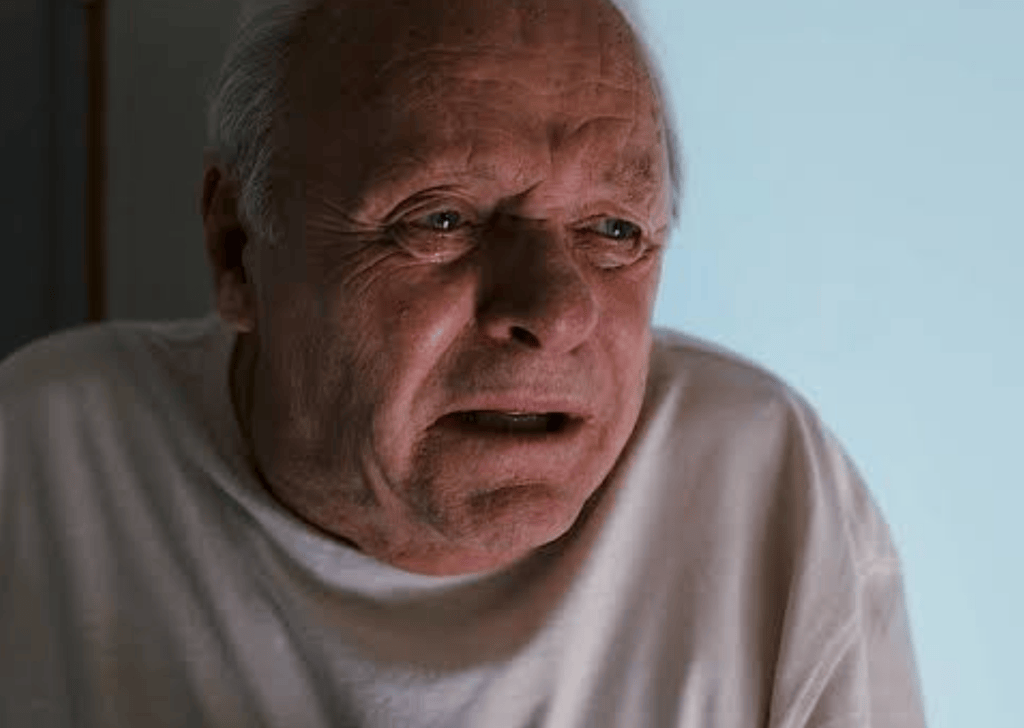 Close-up of an elderly man with a distressed expression, wearing a white shirt, conveying emotions of concern or fear.